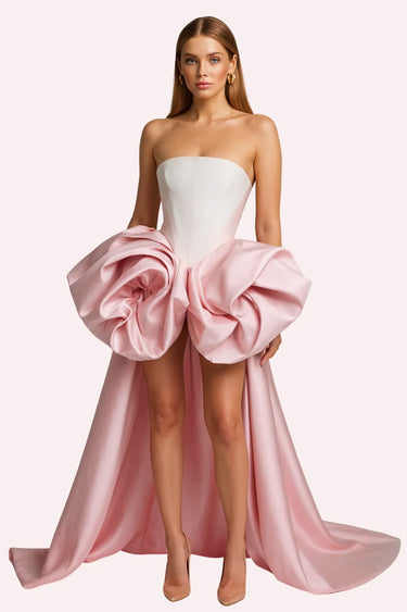 Woman wearing a strapless gown with a large pink ruffle on a white background